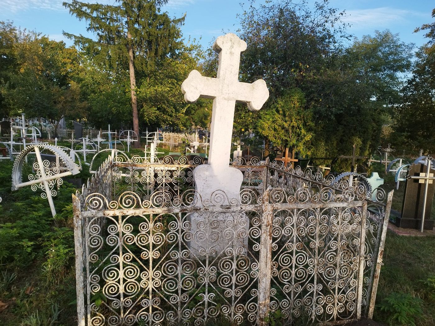 Crucea de piatră din cimitir, în împrejmuirea ei de fier forjat