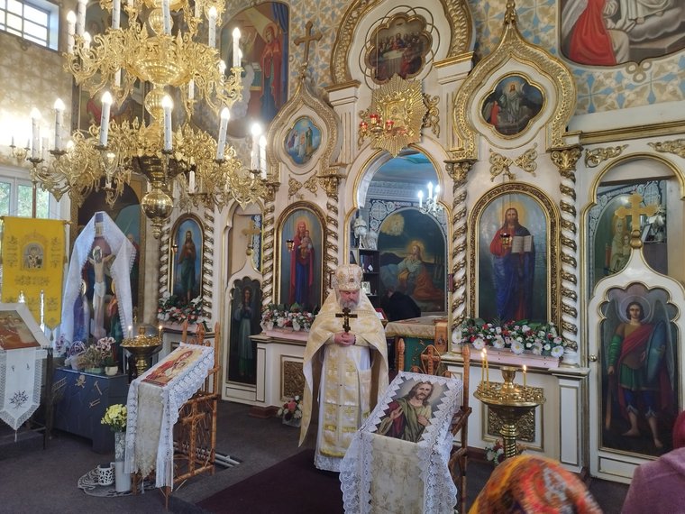 Părintele cu Sfânta Cruce în mâini, în fața ușilor împărătești