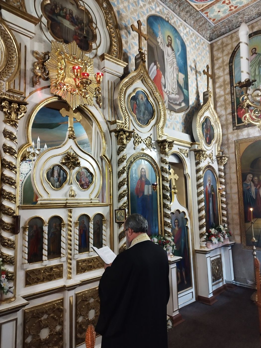 Părintele citind la iconostas, sâmbătă seara