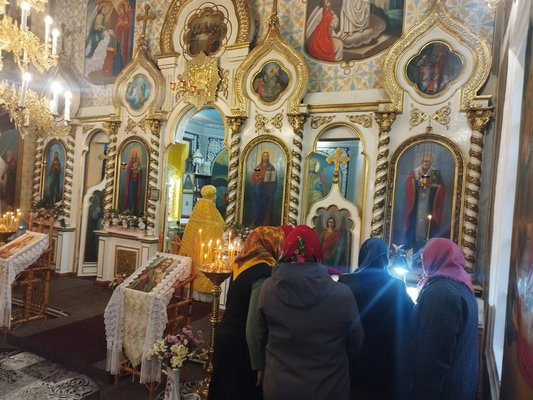 Credincioase la iconostas; în stânga, părintele