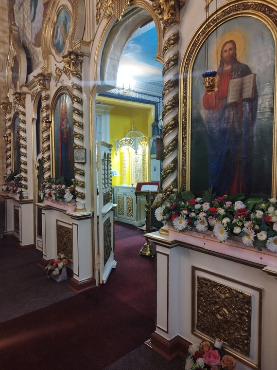 Ușa diaconească deschisă și icoana Mântuitorului, între flori