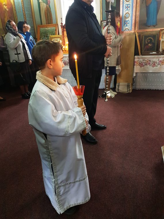 Un băiețel în stihar, cu lumânarea aprinsă