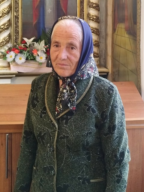 Maria Ciornea, dăscălița bisericii din Sauca, cu basma albastră, în fața iconostasului